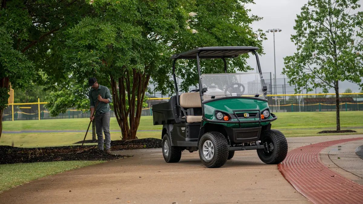 Cushman Hauler PRO verde con cassone in polietilene durante la manutenzione del verde in un impianto sportivo